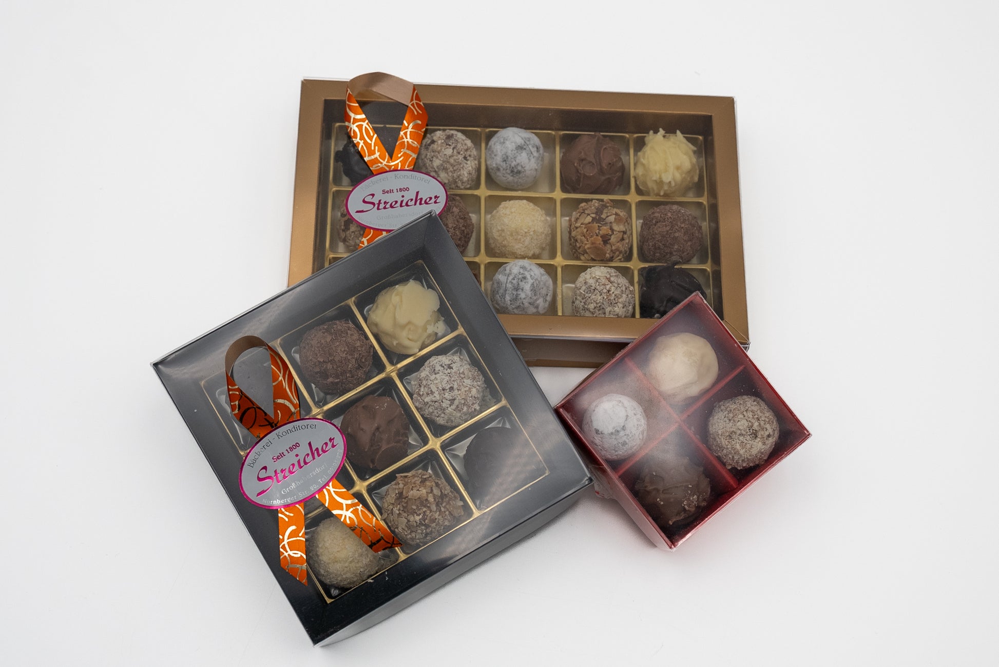 Drei geschlossene Prallinen Schachteln mit handgemachten Sahne-Trüffeln der Bäckerei-Konditorei Streicher