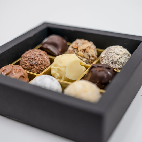 Nahaufnahme von 9 handgefüllten Sahne-Trüffeln, gemischte Sorten. 