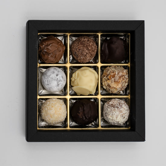 Nahaufnahme von 9 handgefüllten Sahne-Trüffeln, gemischte Sorten. 